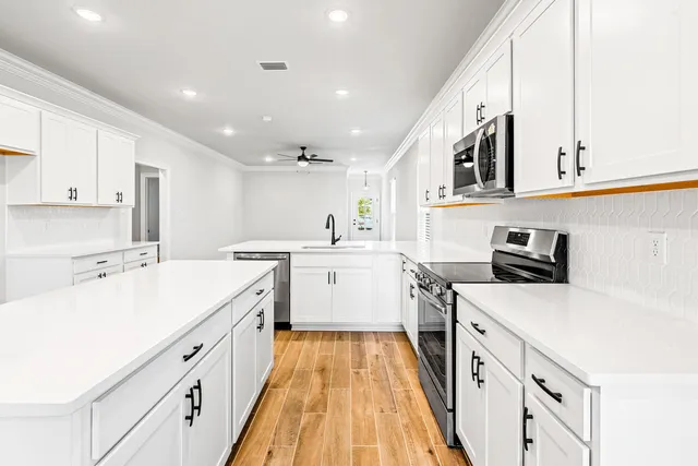 a kitchen with a sink a counter top space stainless steel appliances and cabinets