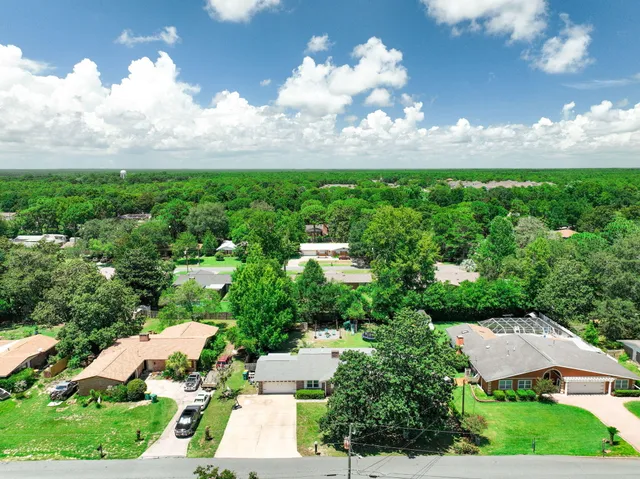 an aerial view of residential houses with outdoor space and trees