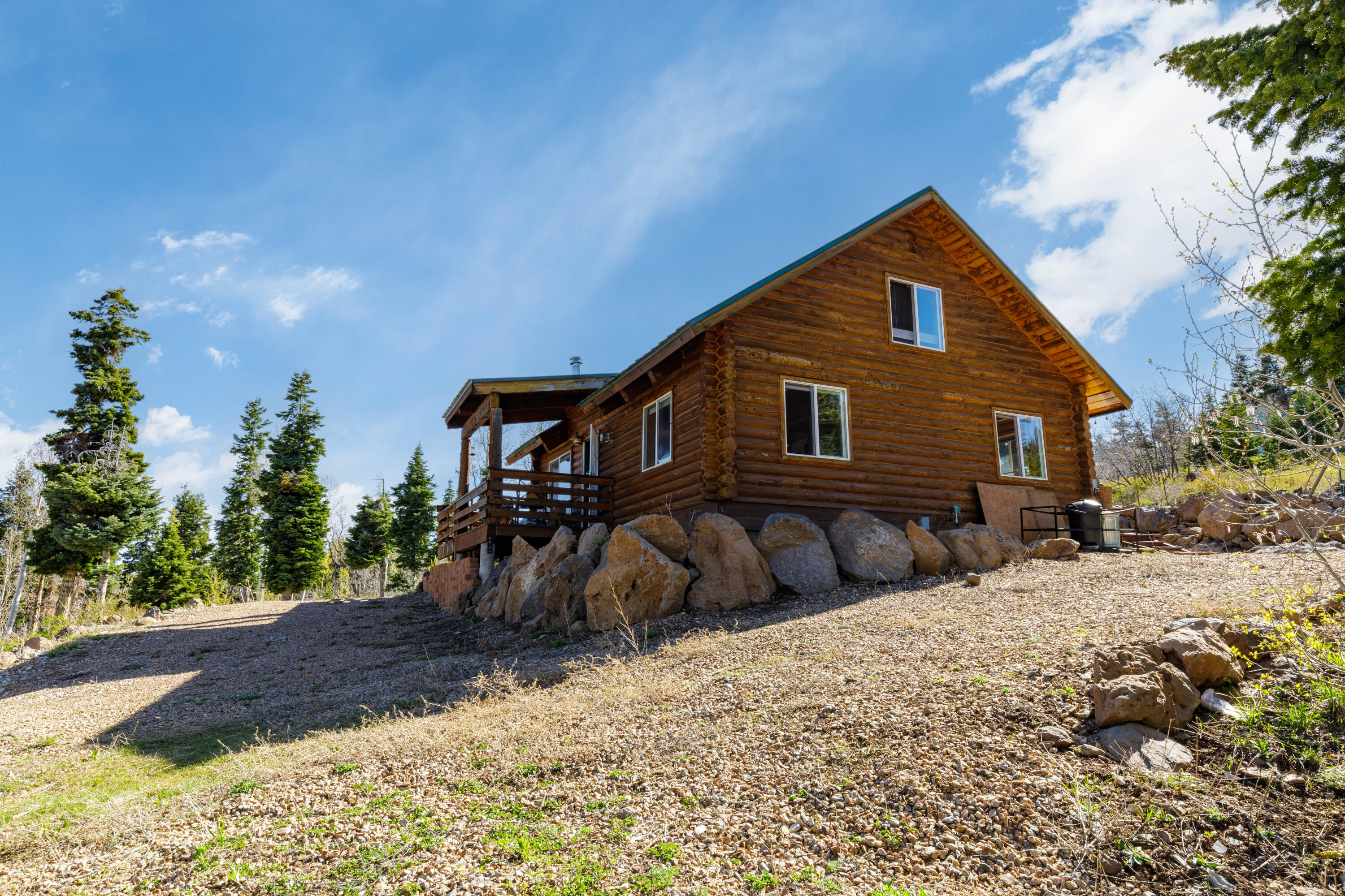 706 West Tranquility Drive Springdale, UT 84767 - Photo 33 of 58 Classic Log Cabin Charm: Low-angle shot highlighting the stone foundation and log walls.
