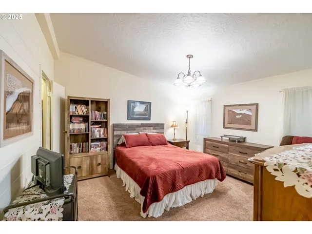 a spacious bedroom with a bed a dresser and painting