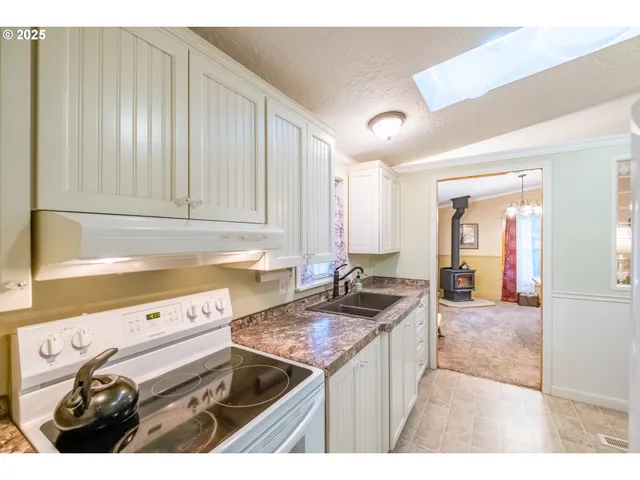 a kitchen with granite countertop a sink a stove and cabinets