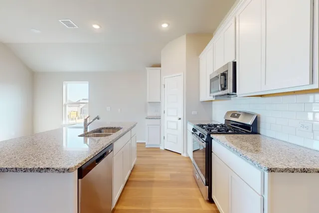 a kitchen with stainless steel appliances granite countertop a sink and a stove