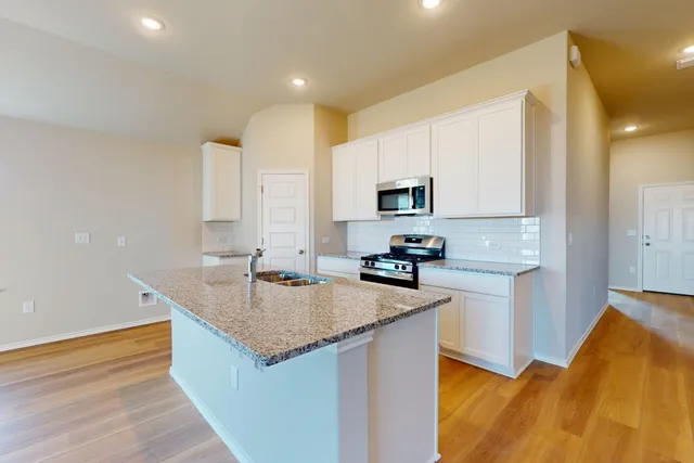 a kitchen with stainless steel appliances granite countertop a sink stove and refrigerator