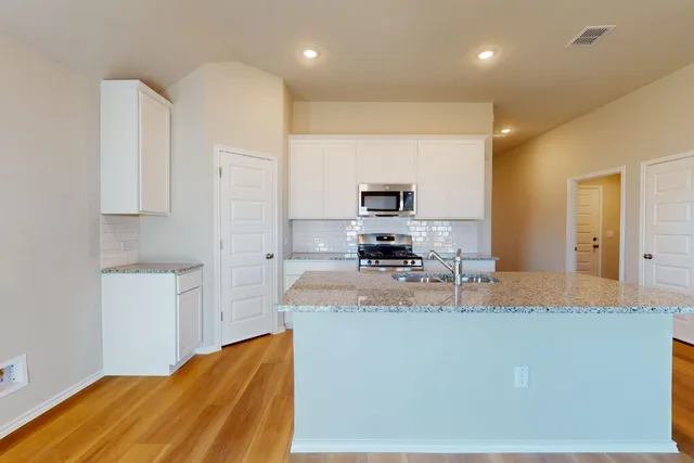 a large kitchen with kitchen island granite countertop a sink a stove a refrigerator a washer and dryer