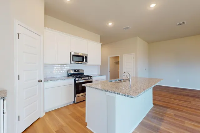 a kitchen with granite countertop a sink stove and refrigerator