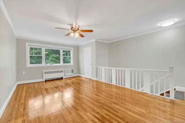 a view of an empty room with a window and wooden floor