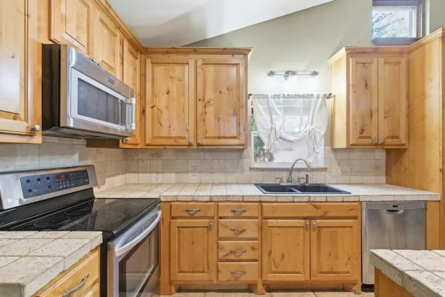 a kitchen with stainless steel appliances granite countertop a sink stove and cabinets