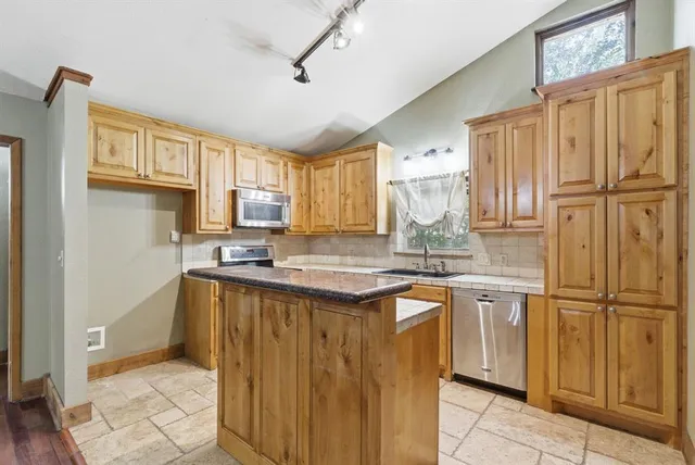 a kitchen with stainless steel appliances granite countertop a stove refrigerator and cabinets