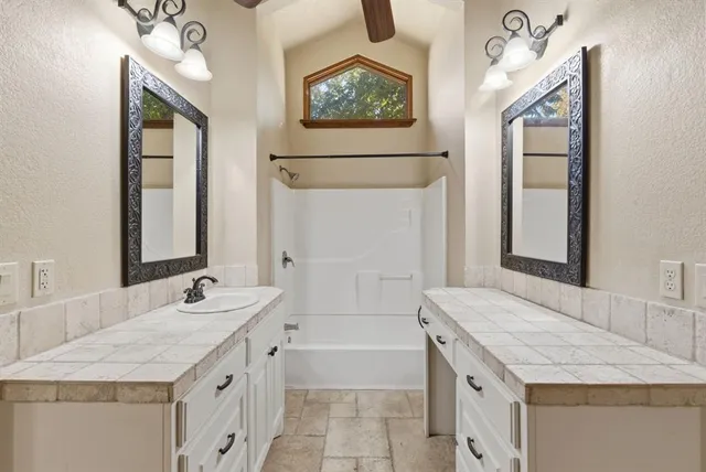 a bathroom with a granite countertop tub sink and mirror