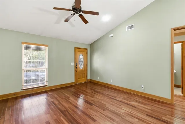 an empty room with wooden floor closet and windows
