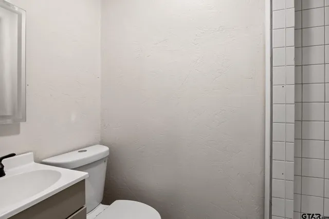 a white toilet sitting next to a white sink and vanity