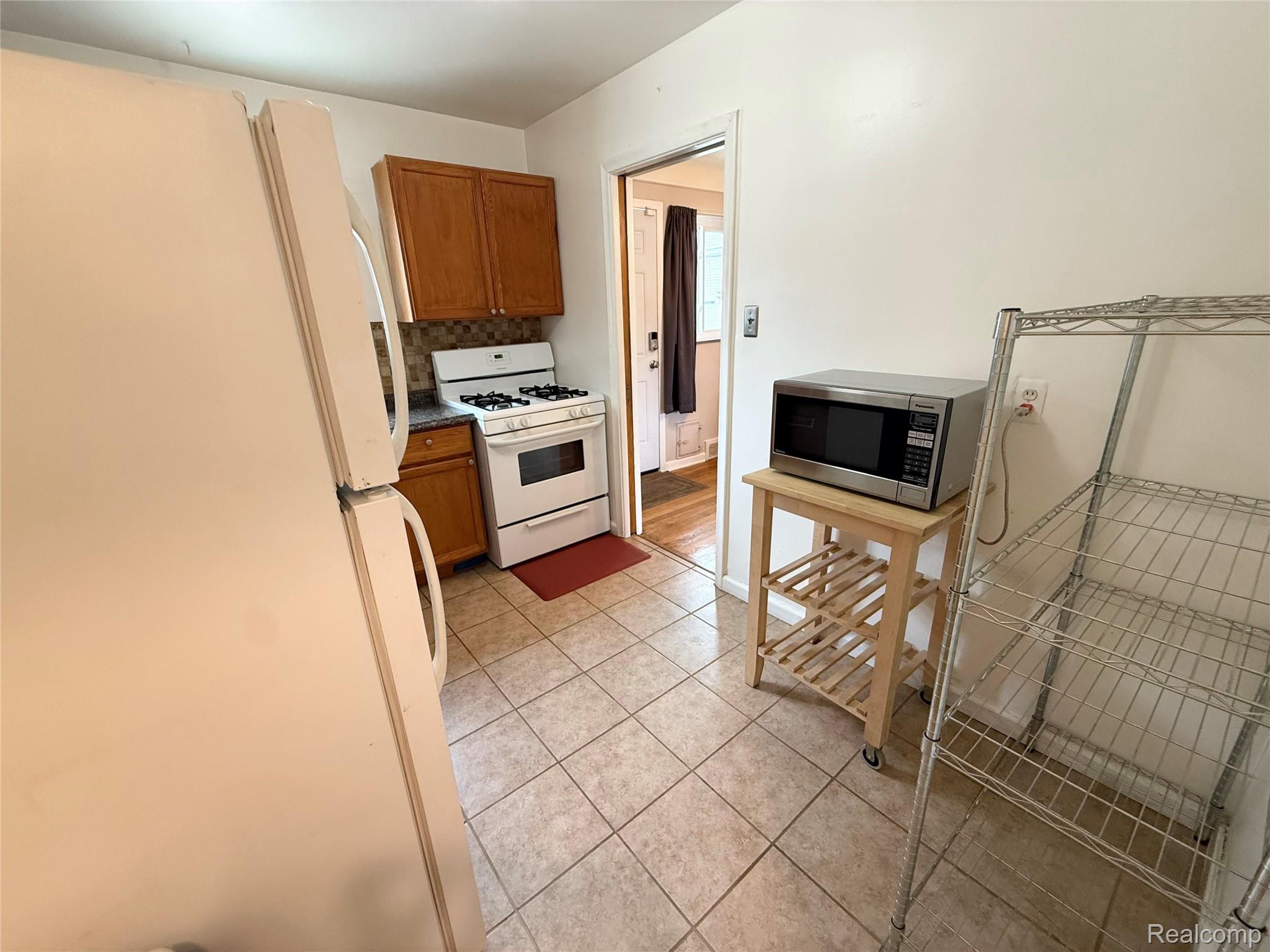 11012 Middlebelt Road Livonia, MI 48150 - Photo 6 of 14 Kitchen featuring tile flooring, white gas range, and wood-finish cabinetry
