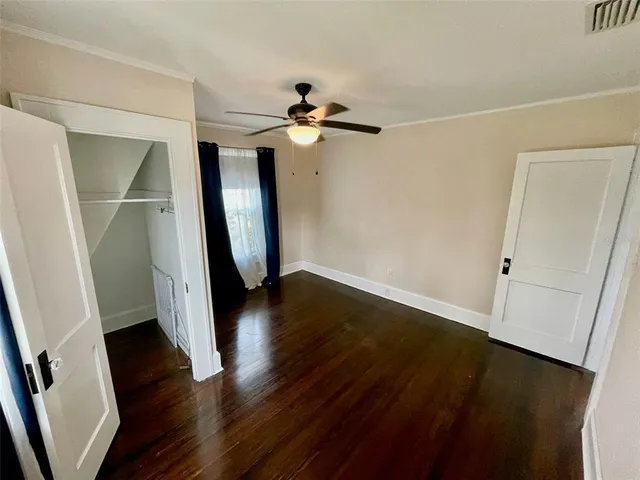 an empty room with wooden floor ceiling fan and window