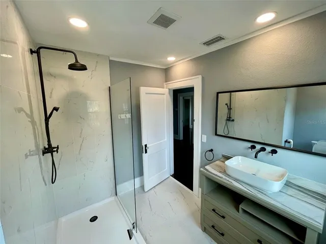 a bathroom with a granite countertop sink a mirror and shower