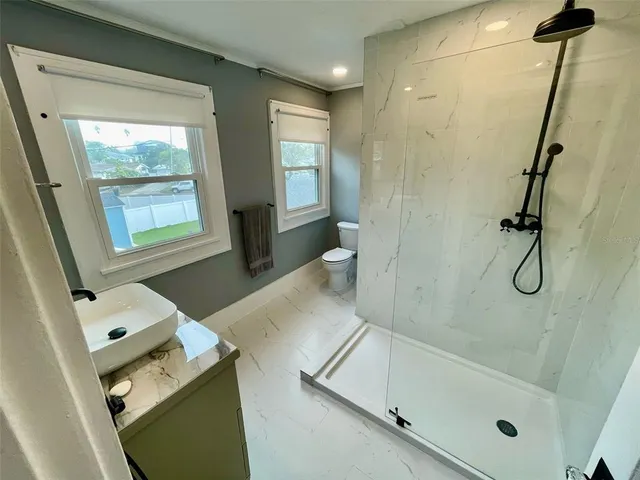 a bathroom with a granite countertop sink a mirror and shower