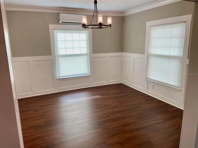 an empty room with wooden floor cabinet and windows