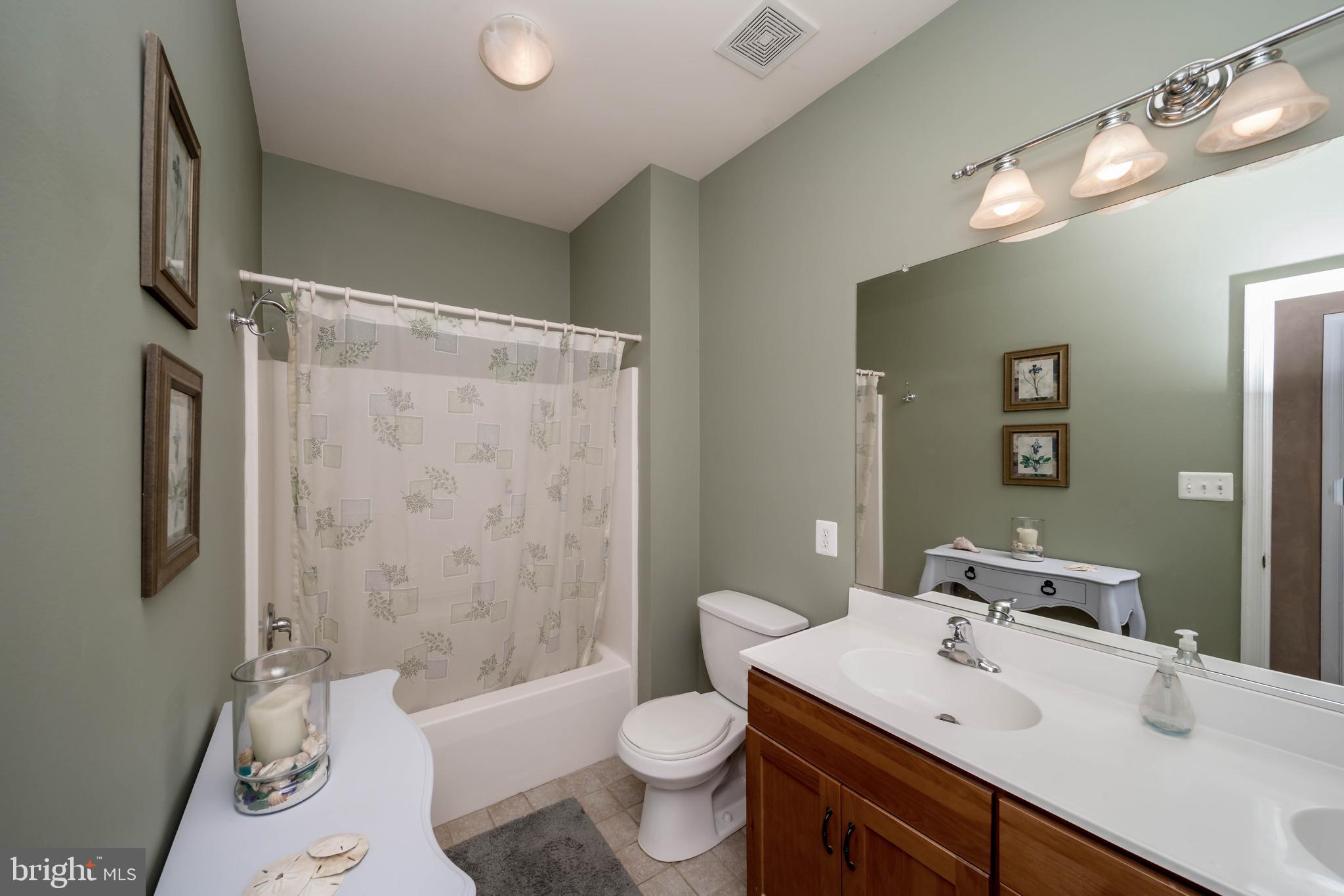 7295 Flint Hill Road Owings, MD 20736 - Photo 19 of 39 a bathroom with a sink a toilet a mirror a vanity and shower