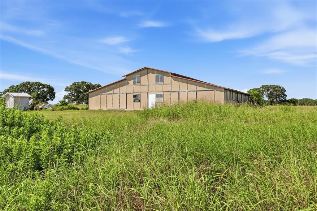 12190 Bell Road Pilot Point, TX 76258 - Photo 35 of 39 Large agricultural building with a prominent gable roofline, multiple window openings, and a single entry door