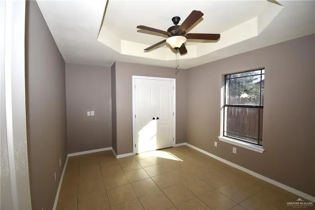 an empty room with windows and ceiling fan
