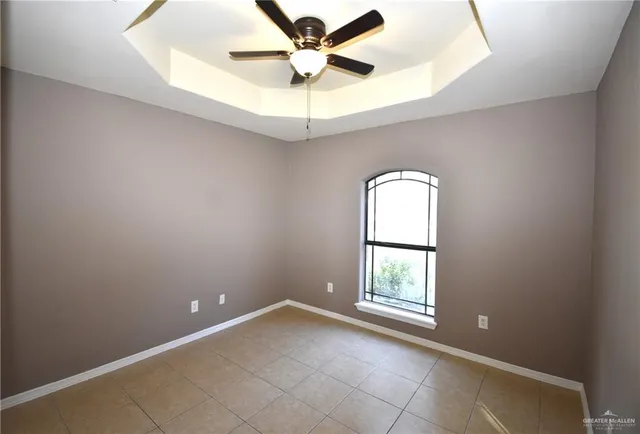 an empty room with a window and a chandelier fan