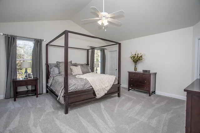a bedroom with a large bed and a chandelier fan