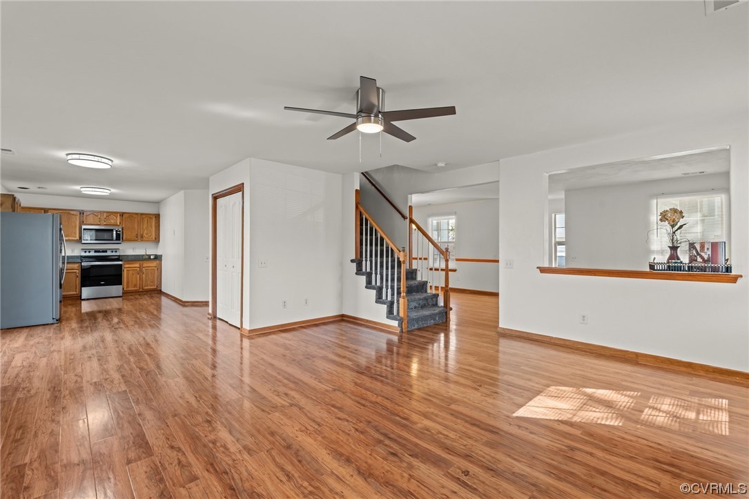 131 Stoney Ridge Avenue, Unit 52 Suffolk, VA 23435 - Photo 10 of 36 a view of an empty room and kitchen with wooden floor and a ceiling fan