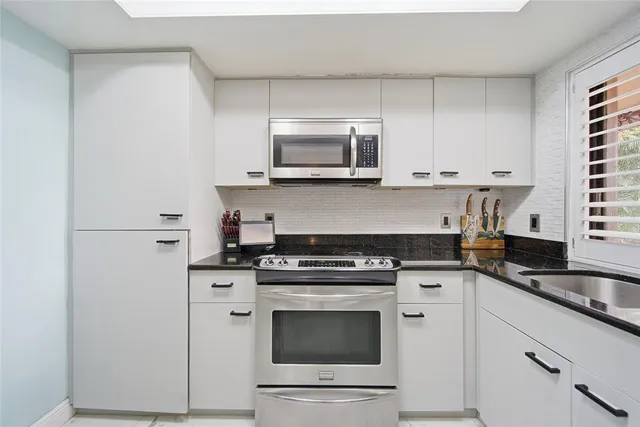 a kitchen with stainless steel appliances granite countertop a stove a sink and a microwave