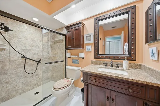 a bathroom with a granite countertop sink a toilet a mirror and shower