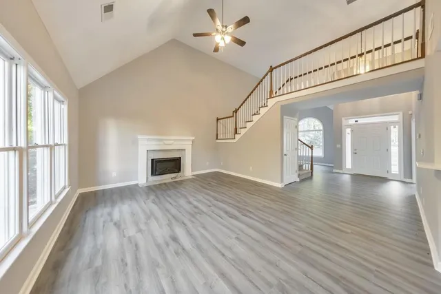 a view of empty room with wooden floor and fan