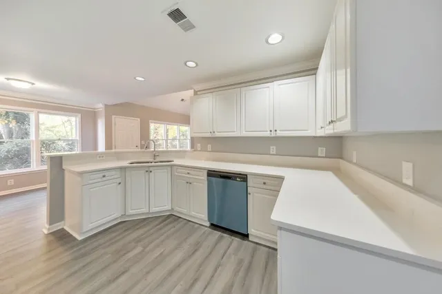 a kitchen with white cabinets appliances a sink and a window