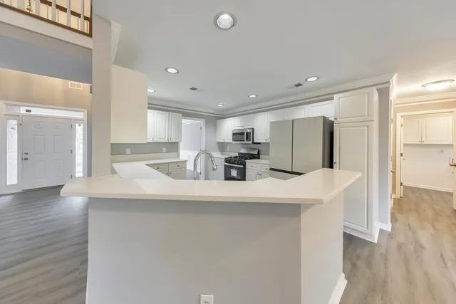 a kitchen with stainless steel appliances granite countertop a refrigerator a sink dishwasher a stove and a refrigerator with wooden floor