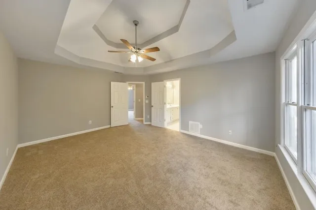 an empty room with windows and fan