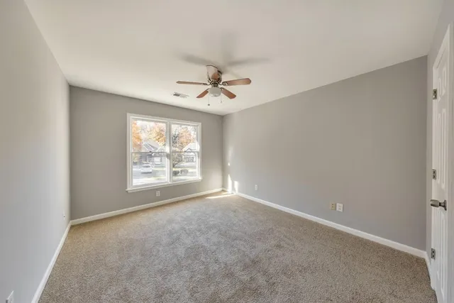 an empty room with windows and fan