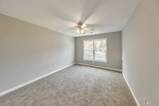 an empty room with windows and ceiling fan