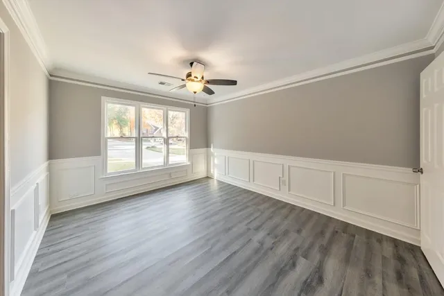 an empty room with wooden floor chandelier fan and windows