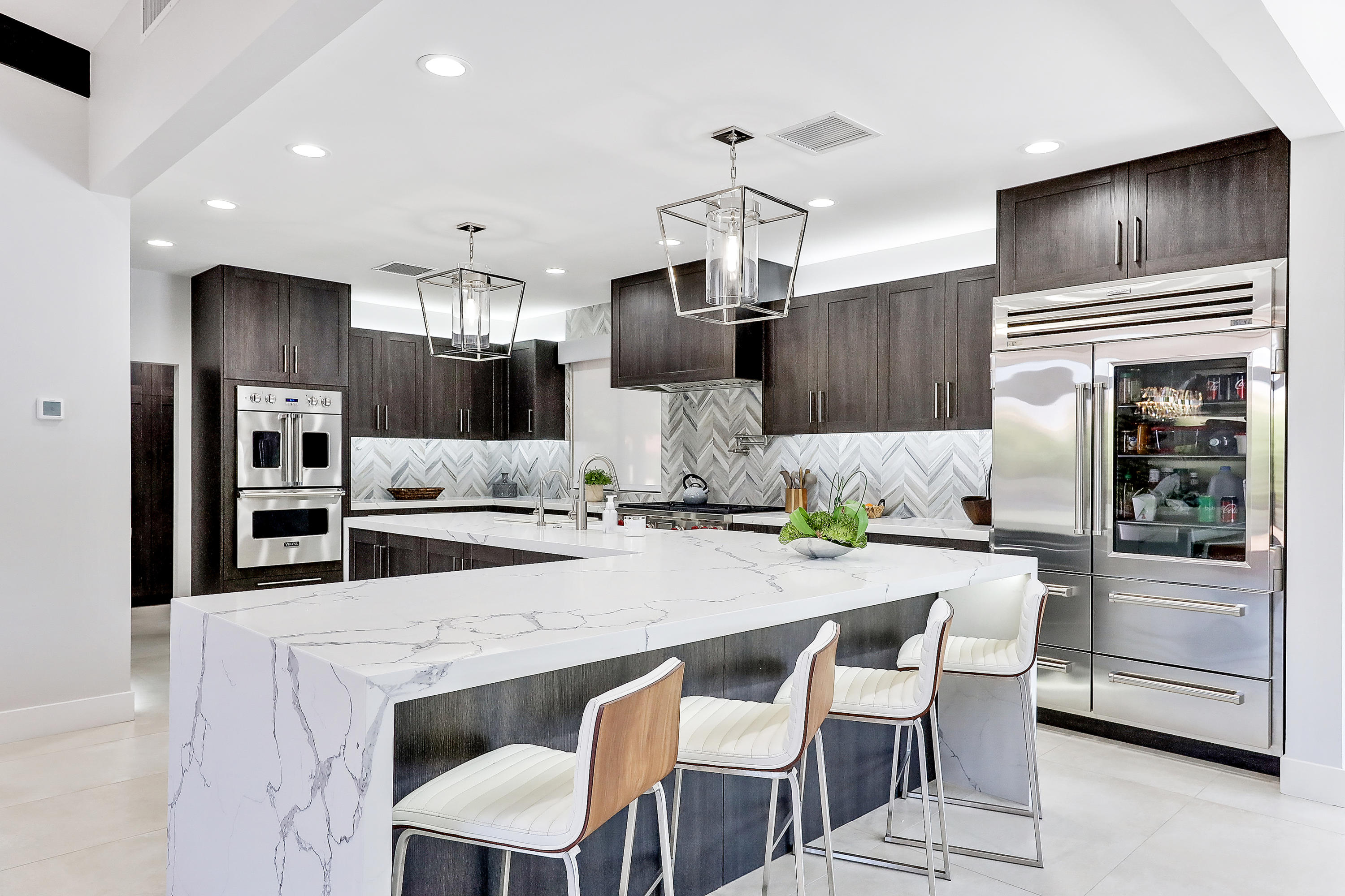 45731 Paradise Valley Road Indian Wells, CA 92210 - Photo 13 of 41 a kitchen with stainless steel appliances kitchen island granite countertop a table chairs and a refrigerator