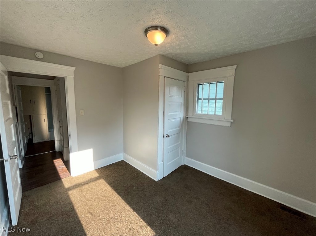 950 Avon Street Akron, OH 44310 - Photo 11 of 15 Unfurnished bedroom featuring baseboards, dark colored carpet, and a textured ceiling