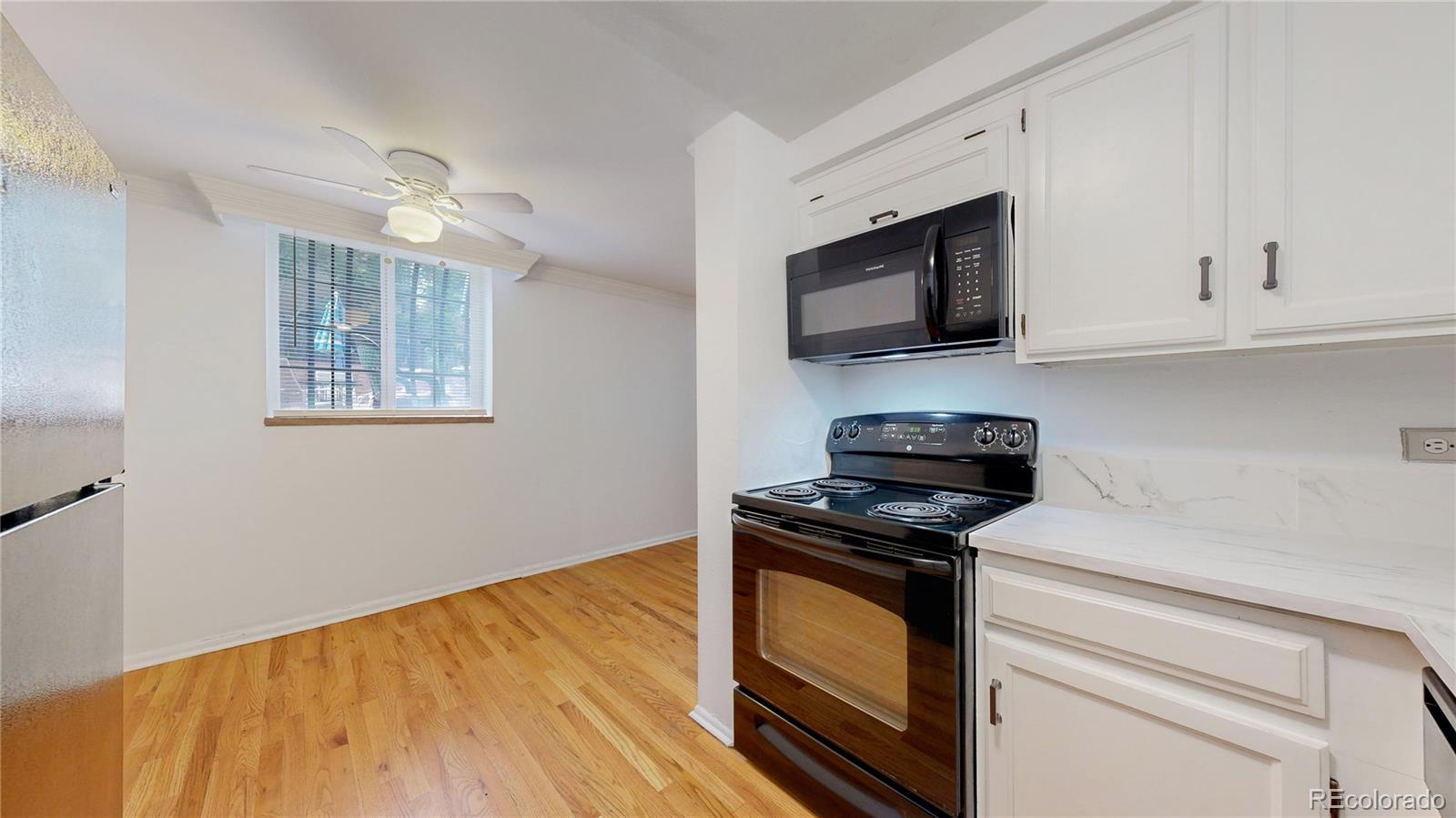 1350 Josephine Street, Unit 101A Denver, CO 80206 - Photo 13 of 36 a kitchen with granite countertop cabinets stainless steel appliances and wooden floor