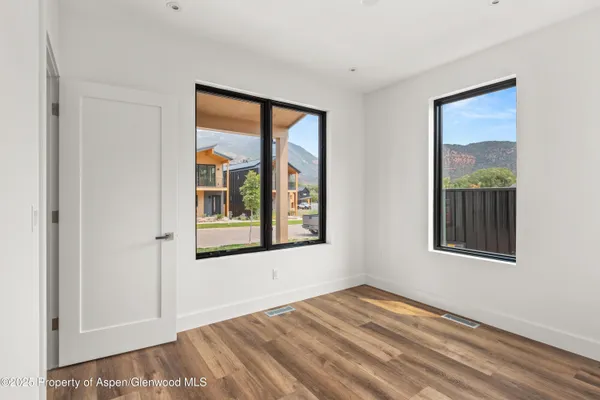 a view of an empty room with a window and wooden floor