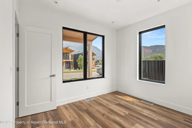 a view of an empty room with a window and wooden floor