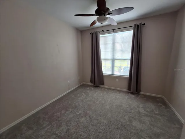an empty room with windows and ceiling fan
