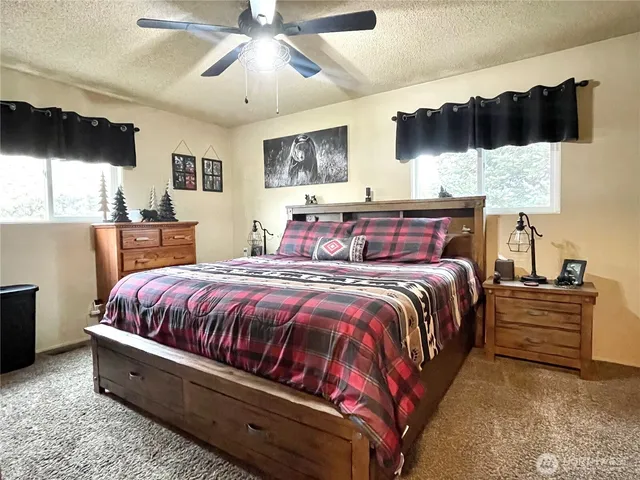 a bedroom with a large bed a flat tv screen and dresser next to a window
