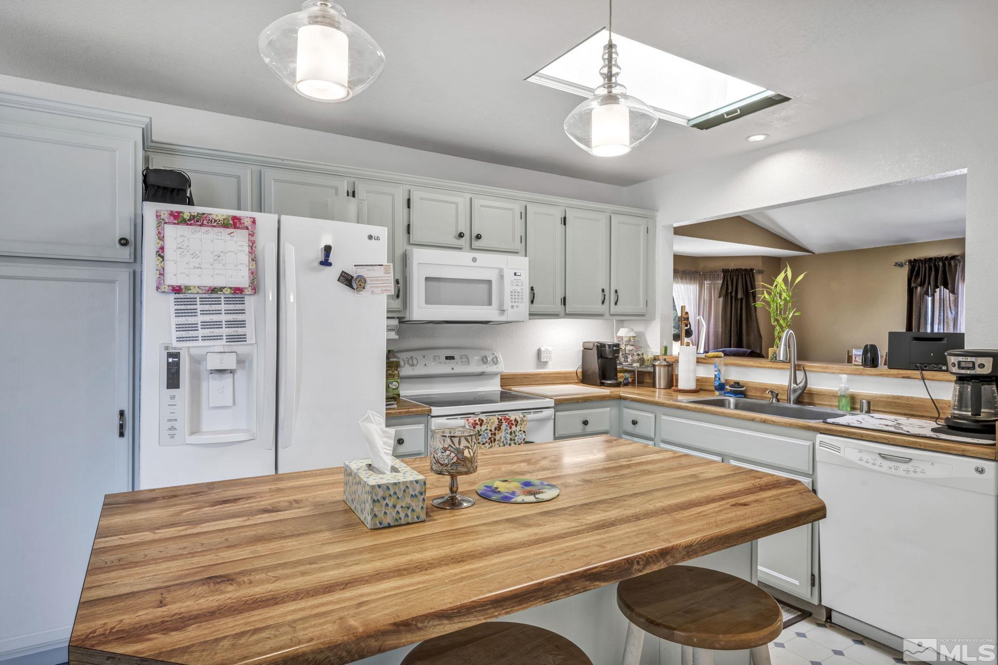 17575 Blackbird Drive Reno, NV 89508 - Photo 11 of 29 a kitchen with stainless steel appliances granite countertop a refrigerator a sink dishwasher a stove a dining table and chairs with wooden floor