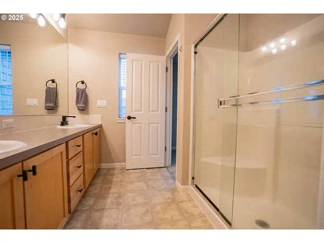 a bathroom with a double vanity sink a mirror and shower
