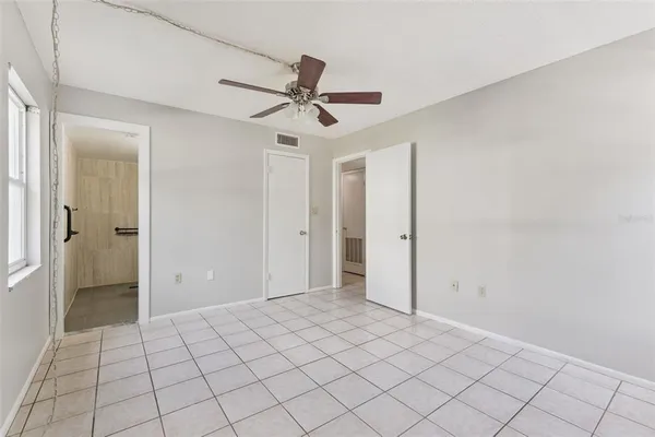 an empty room with closet and a chandelier fan
