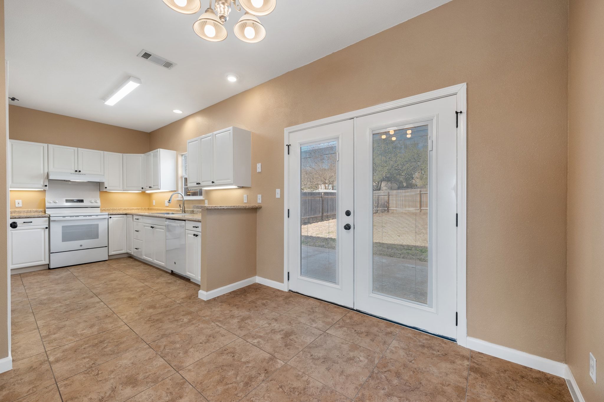 3139 Chisholm Trail Austin, TX 78734 - Photo 14 of 37 Kitchen with french doors, white appliances, white cabinetry, and a chandelier