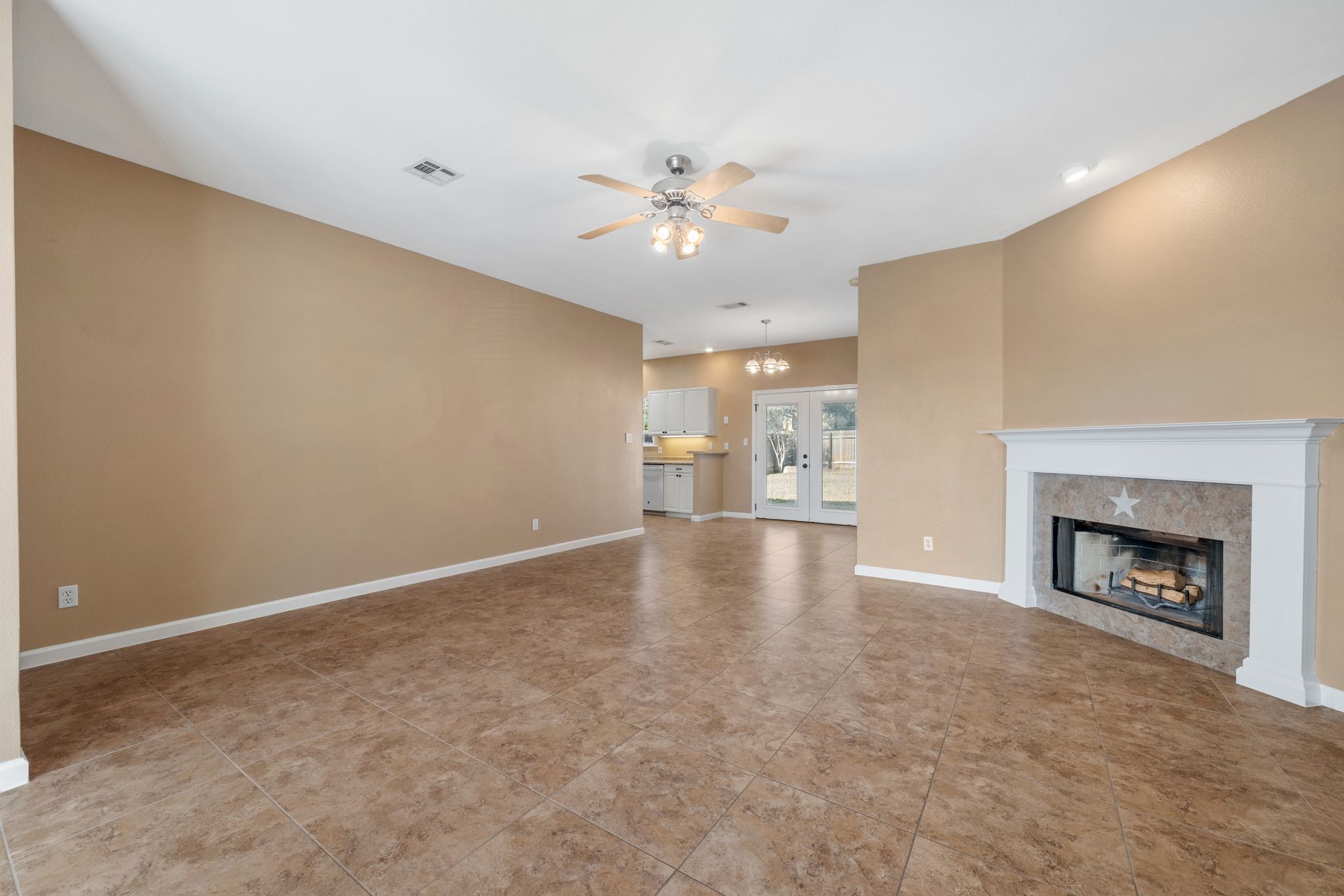 3139 Chisholm Trail Austin, TX 78734 - Photo 9 of 37 Unfurnished living room with ceiling fan, a tiled fireplace, french doors, and light tile patterned floors