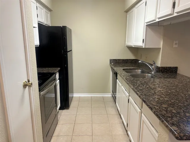 a kitchen with granite countertop a refrigerator and a sink