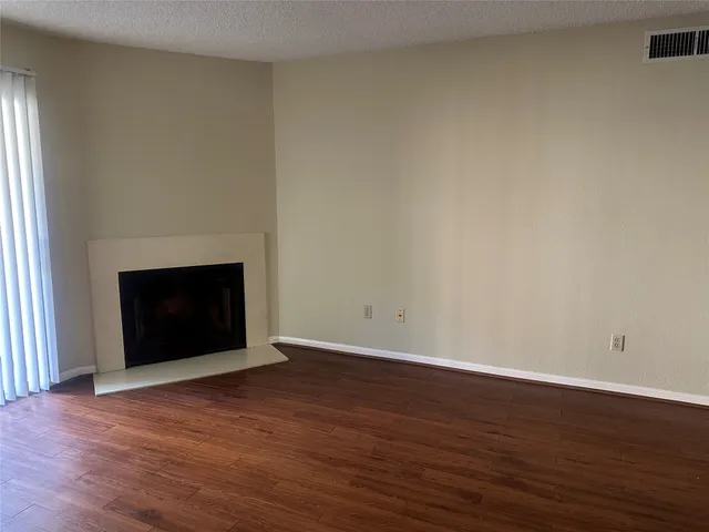 an empty room with wooden floor and fireplace