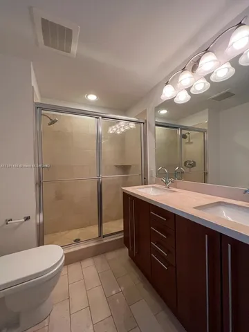 a bathroom with a granite countertop sink a toilet a mirror and shower